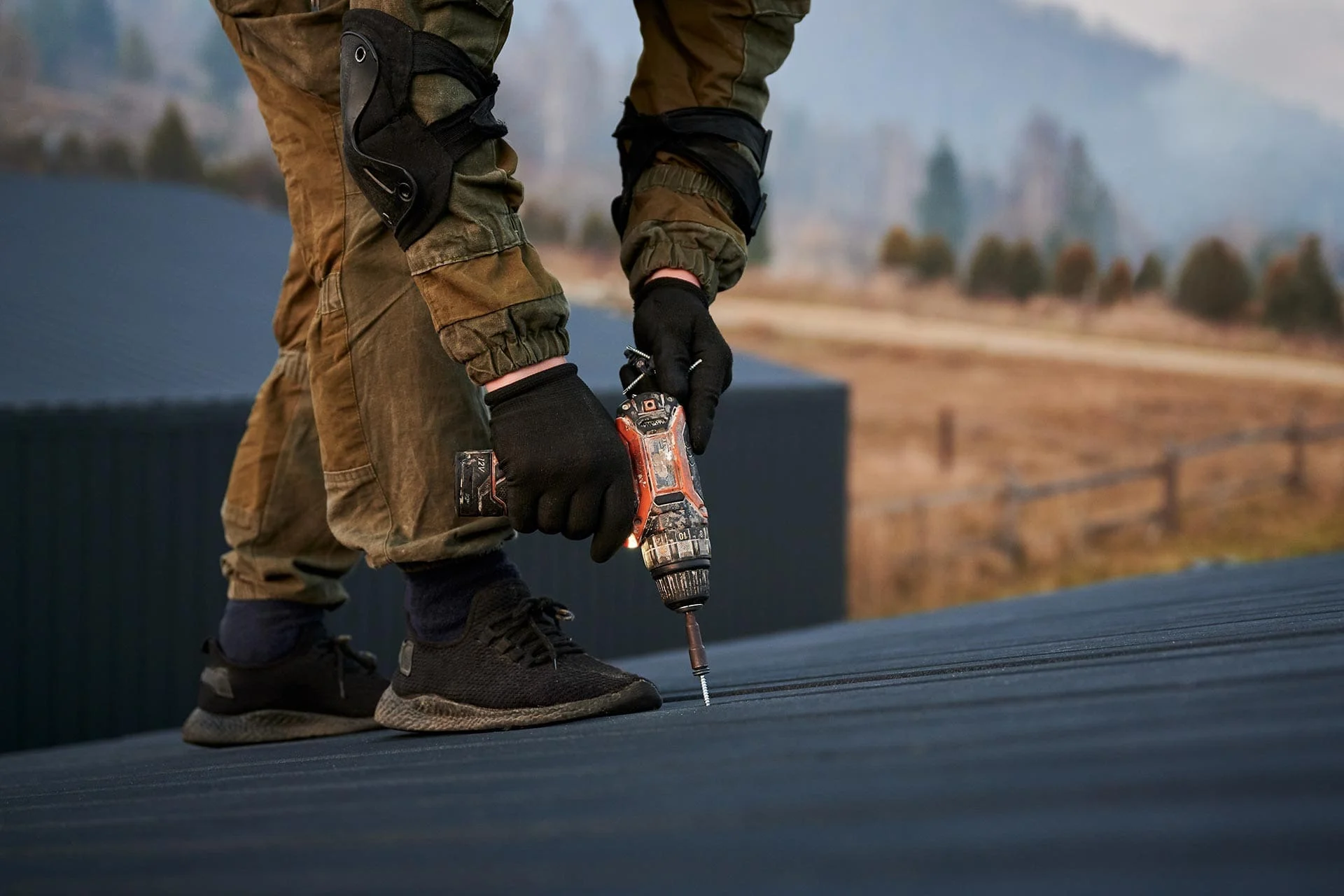 Close-up of a roofer fastening a roofing panel