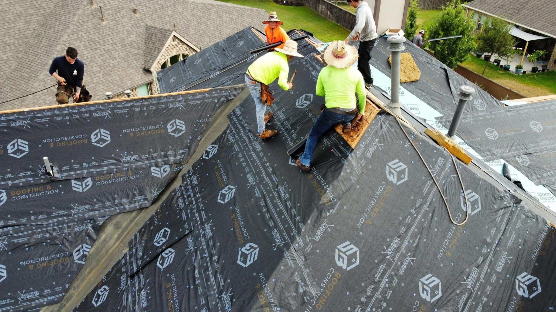 Roofing team installing underlayment on a residential home